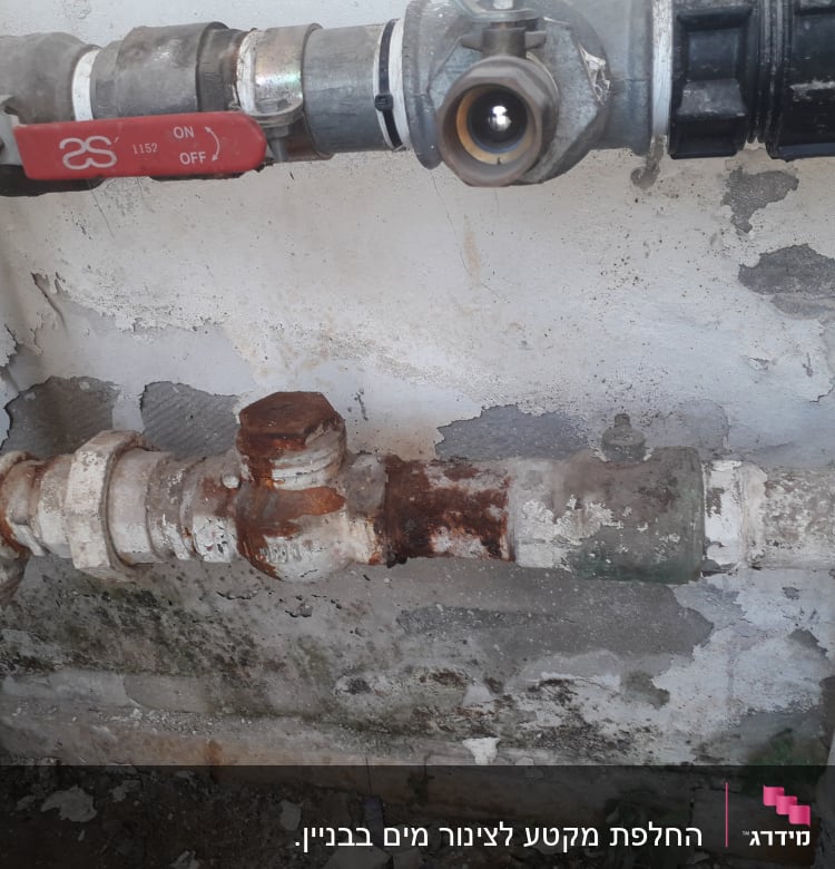 צינור חלוד עם ברז אדום על קיר מתקלף